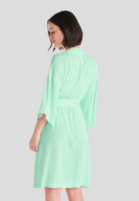 Ropa de color verde claro con una textura suave, mangas cortas de kimono, un lazo en la cintura y un sutil patrón de puntos en toda la prenda.