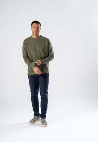 Olivengrøn sweatshirt med en rund halsudskæring, ribbede manchetter og kant; parret med marineblå bukser og grå snøresko. Simple, rene linjer.