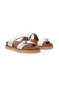 Hvide sandaler med to brede stropper og en metallisk detalje. Brun fodseng på en lys tan, tekstureret gummisål. Afslappet design.