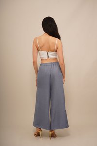 Pantalons larges gris clair en tissu texturé, associés à un haut court blanc avec une bordure en dentelle et une fermeture éclair dans le dos.