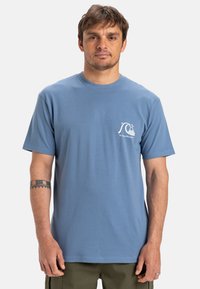 Lichtblauw katoenen T-shirt met korte mouwen, ronde hals en een kleine witte golfafbeelding op de linkerkant van de borst. Effen textuur en een ontspannen pasvorm.