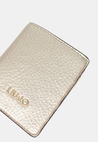 Portafoglio in pelle dorata e testurizzata con finitura liscia, caratterizzato dal logo a caldo "LIU•JO" in oro sul davanti. Forma rettangolare compatta.