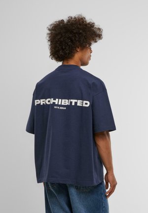 Navyfarbenes Oversized-T-Shirt mit weißer Blockschrift "PROHIBIERT 10119, BERLIN" auf dem Rücken. Kurze Ärmel, runder Halsausschnitt, aus Baumwollmaterial.