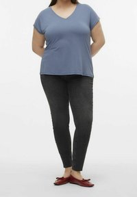 T-shirt blu con maniche corte a V abbinato a jeans slim-fit scuri e ballerine rosse con dettagli a fiocco. Tessuto morbido con vestibilità comoda.