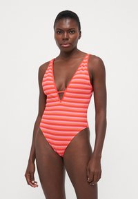 Maillot de bain une pièce rayé rouge et orange avec un décolleté en V profond et un détail découpé. Fabriqué à partir d'un tissu lisse et extensible.