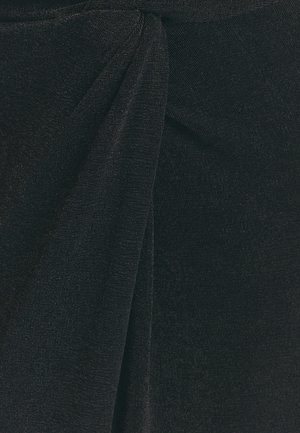 Juoda audinio medžiaga su minkšta, briaunuota tekstūra, juosmenyje turi susuktą detalę, kuri sukuria klostes, pridedančias vizualų žavesį.