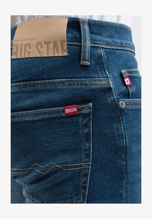 Tmavomodré džíny z denimu s koženou nášivkou "BIG STAR", červeným šitím a malými červenými štítky na kapsách.