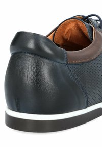 Granatowe skórzane sneakersy z brązowymi akcentami, perforowanymi bokami, wyściółką z amortyzacją oraz białą gumową podeszwą. Zaokrąglony detal obcasa.