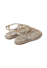 Sandalias planas con correas metálicas doradas y hebilla en el tobillo, que cuentan con una plantilla de ante beige claro y una suela texturizada marrón.