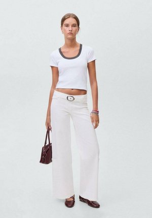 White cropped t-shirt with a gray neckline, paired with wide-leg white trousers. Accessories include a burgundy handbag and brown flats.