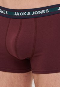 Burgunderfarbene Boxershorts aus weichem Stoff, mit einem kontrastierenden elastischen Bund, der das Logo "JACK & JONES" in weißem Text trägt.