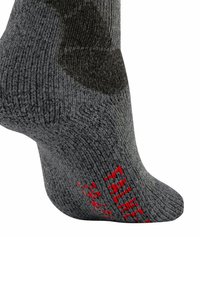 Chaussette tricotée grise avec une texture côtelée, un talon renforcé et des lettres rouges sur le côté. Le design inclut des nuances légèrement plus foncées.