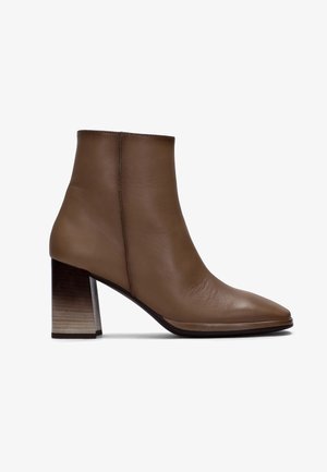 Botín de cuero marrón hasta el tobillo con punta afilada, textura suave y un tacón de madera grueso y ligeramente cónico con un suave degradado.