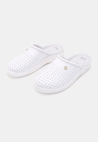 Sabots blancs à enfiler avec un design perforé et un accent doré sur le côté; fabriqués à partir d'un matériau lisse et flexible avec une semelle rembourrée.