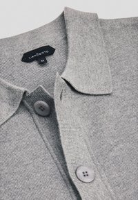 Jasnoszary sweter polo z kołnierzykiem, z dwoma szarymi guzikami i metką oznaczoną "LANCERTO" oraz rozmiarem "M."