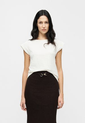 Biały krótki rękaw top połączony z ciemną prążkowaną spódnicą z boczną klamrą paska, prezentowany na jednolitym tle.