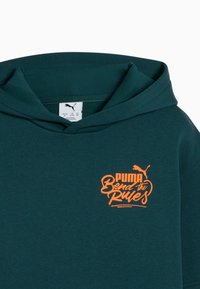 Felpa verde scuro con tasca a marsupio e una grande scritta grafica arancione che recita "PUMA Bend the Rules". Materiale morbido in cotone.