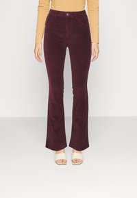 Burgundy corduroy flared pants with a high waist, front pockets, and a single button closure. Features a soft texture and slight sheen.