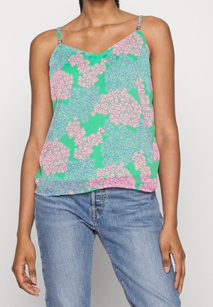 Ærmeløs grøn top med pink og blå blomsterprint, båret med blå jeans, vist fra skuldre til hofter.