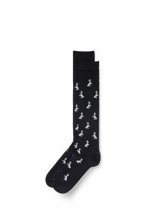Black socks with an all-over white dog pattern. Features a smooth texture and ribbed cuffs for comfort.