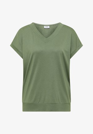 Femme aux cheveux courts marron portant un haut vert olive à manches courtes et un jean en denim bleu, vue de dos sur un fond uni.
