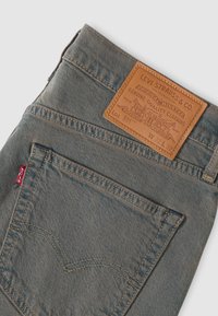 Γκρι τζιν Levi's 511 που εμφανίζουν την πίσω τσέπη με πορτοκαλί ραφές και καφέ δερμάτινο ετικέτα μάρκας με μέγεθος W32 L32.