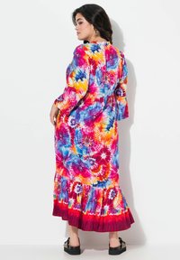 Dlouhé tie-dye šaty s živými barvami růžové, modré, oranžové a fialové. Volné rukávy a volánkový lem. Měkká textilie.