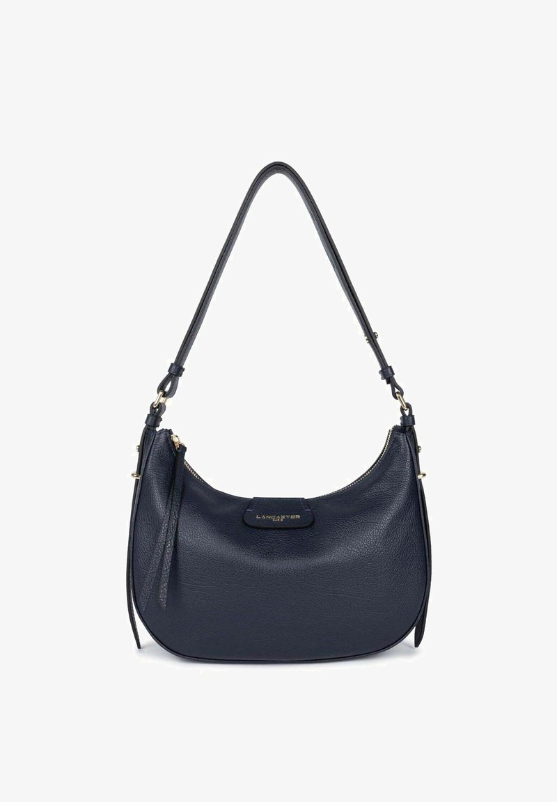 Sac à bandoulière en cuir navy au design courbé, avec des accessoires dorés et un petit détail zippé. Surface texturée avec un patch de logo.