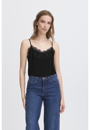 Zwarte satijnen cami met kantafwerking, gecombineerd met hooggewaisted blauwe spijkerbroek, met een vervaagde textuur en knoopsluiting.
