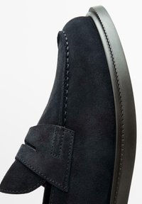 Marineblauwe suède instapschoen met een platte rubberen zool, voorzien van een gestikt ontwerp en een gevouwen accent op de wreef voor een stevige pasvorm.