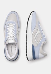 Jasnoniebieskie i szare sneakersy wykonane z miękkiego materiału tekstylnego i skóry. Charakteryzują się białymi sznurówkami, srebrnymi akcentami oraz teksturowaną podeszwą.