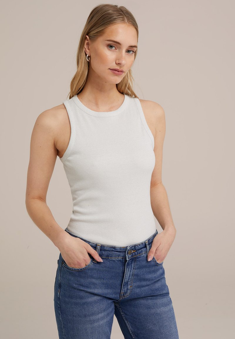 Vit ribbad t-shirt med rund halsringning och ärmlös design, kombinerad med blå hög midja jeans, som visar en figurnära silhuett.