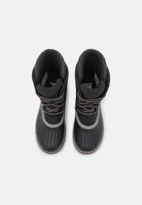 Botas impermeables negras con suelas de goma texturizadas, cuellos acolchados y acentos de cordones en gris metálico. Forro suave gris visible en el interior.