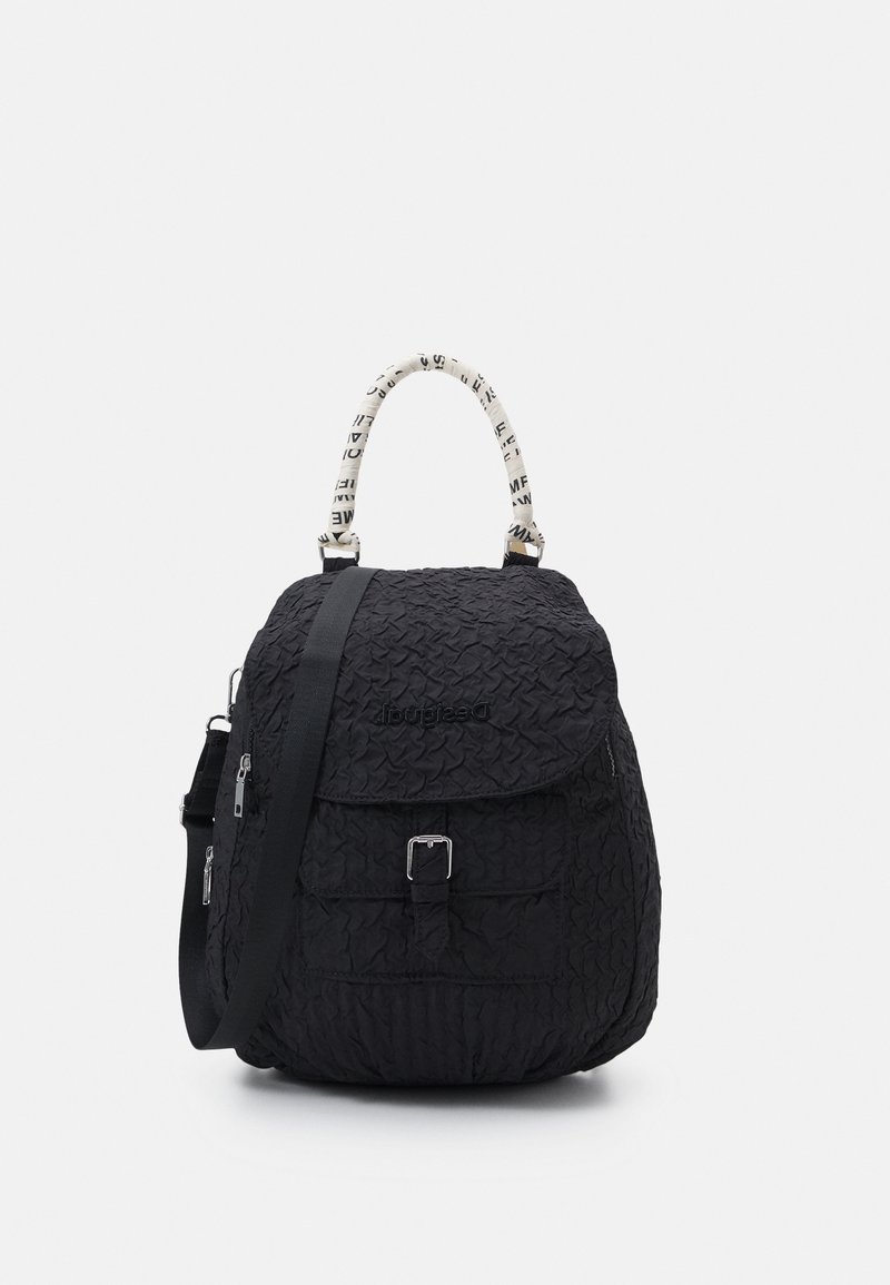 Czarny plecak z teksturowanej tkaniny, o zaokrąglonym kształcie, z białą uchwytem w wzory oraz przednią kieszenią z zapięciem na klamrę.