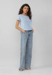 Lichtblauw katoenen t-shirt met korte mouwen en een ronde hals, gecombineerd met high-waisted, wijdvallende lichtgewicht denim jeans met een ontspannen pasvorm.