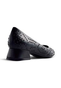 Scarpa in pelle nera con tacco quadrato basso, decorata con accenti chiodati in un motivo a spirale sulla superficie superiore.