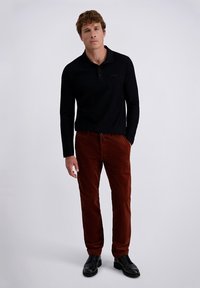 Black long-sleeve polo shirt paired with rust-colored corduroy pants and black lace-up shoes. Plain design with a relaxed fit.
