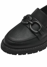 Black leather shoe with a textured upper, featuring a prominent metal buckle accent and a rugged sole with contrast stitching details.