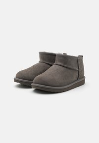 Botines de ante gris con puntera redondeada y una costura cosida, que cuentan con un forro suave y una suela de goma texturizada.
