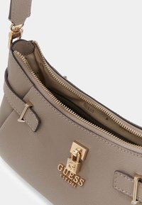 Szara torebka ze skóry o fakturze, z złotymi elementami, zamkiem z przodu oraz dwoma zamykanymi na zamek komorami. Wnętrze wyściełane jest materiałem we wzory.