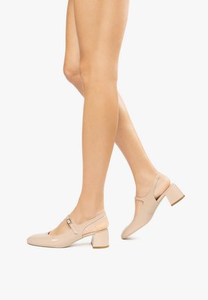 Tacchi slingback in pelle verniciata beige con punta quadrata, tacco basso e cinturino con fibbia, caratterizzati da dettagli a intaglio sui lati.