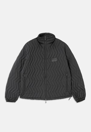Black quilted jacket with chevron stitching, front zipper, zippered side pockets, and a small rectangular patch on the chest.