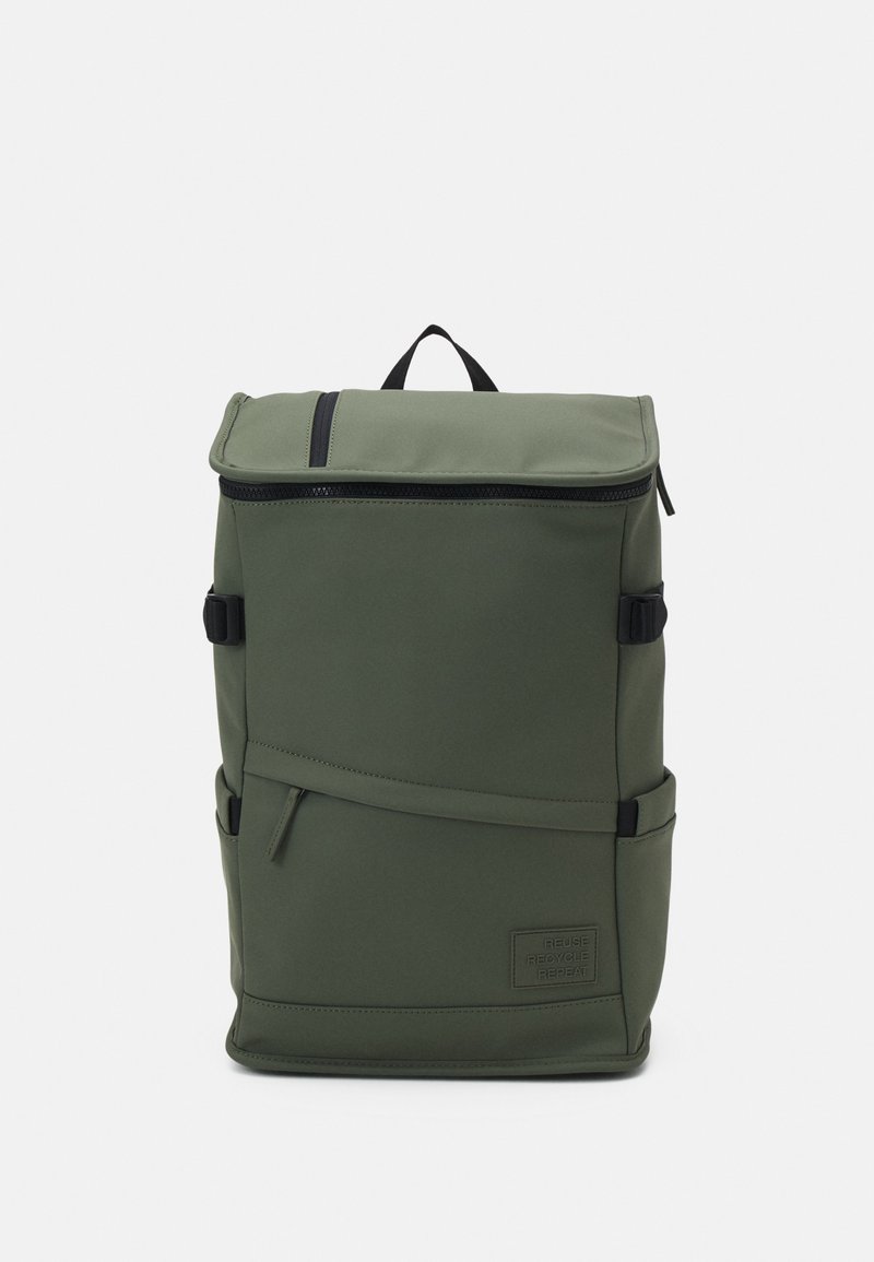 Sac à dos en nylon vert avec un design à rabat, fermeture éclair noire, sangles latérales réglables et une petite étiquette portant la mention "REUTILISER RECYCLEZ REPETEZ."