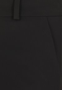 Tessuto nero con una texture liscia, caratterizzato da una vita aderente e cuciture discrete. Non presenta motivi visibili o dettagli in metallo.