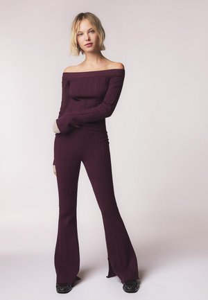 Burgundy ribbet strik two-piece sæt med en off-the-shoulder top og flared bukser med sideslids, lavet af tekstureret materiale.