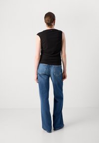Svart ermeløs topp med en tettsittende design, kombinert med høydefinerte blå jeans med rett ben og enkle baklommer.