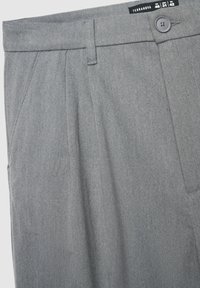 Pantaloni grigi su misura in tessuto textured con frontale piatto, due pince frontali e chiusura con un bottone in vita.