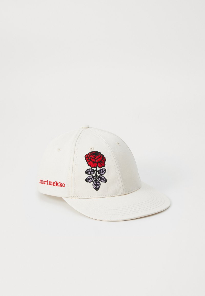 Căciulă albă din bumbac, cu broderie a unei trandafiri roșii și frunze verzi pe față, având textul "marimekko" în roșu pe lateral.