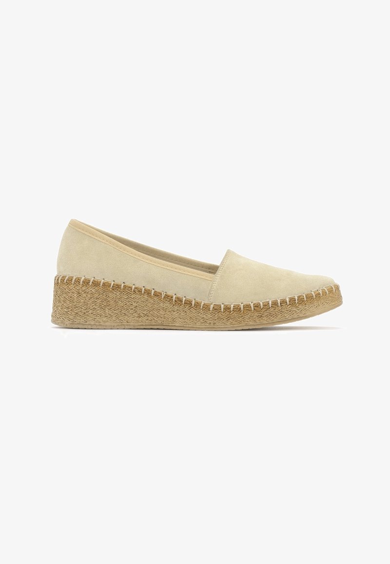 Chaussure compensée en daim beige avec semelle plateforme en jute tissé et couture visible autour du bord de la semelle, vue de côté sur fond blanc.