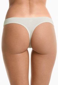 Lichtgroene string gemaakt van een zachte, rekbare stof. Heeft minimale bedekking met een dunne tailleband en een naadloos ontwerp.